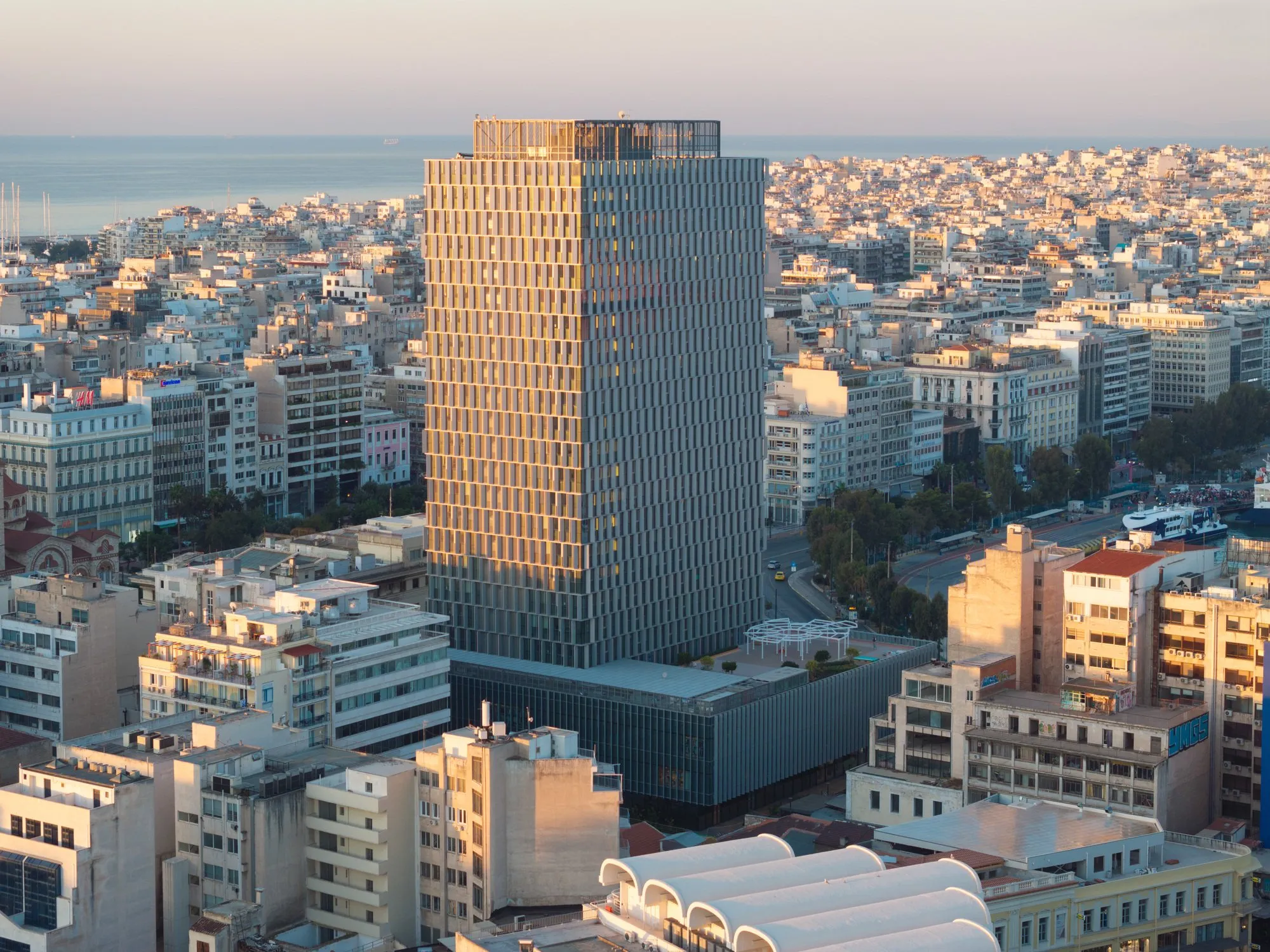 Wieżowiec Piraeus Tower w Pireusie z przeszkloną elewacją, widok od strony portu